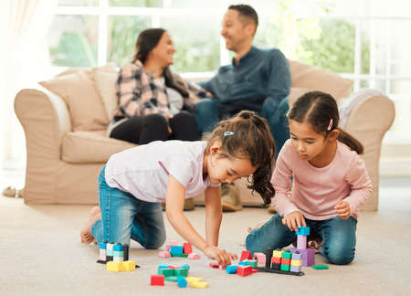 We bond differently. Shot of a young family bonding inn the lounge at home.の写真素材