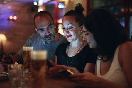 Looks like I have a stalker in here. Shot of friends looking at something on a cellphone while...