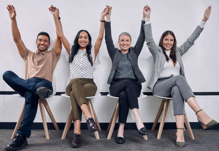 We did a great job. Shot of a group of businesspeople people sitting down with their arms raised.