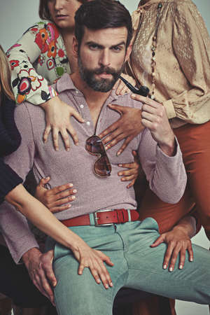Im a ladies man, for sure. Studio shot of an attractive man in retro 70s wear being touched by women...
