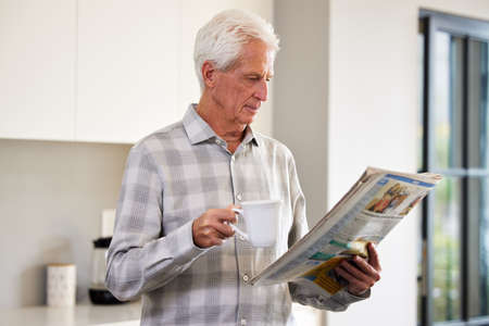 Give me a newspaper and some tea and Im happy. Shot of a mature man reading a newspaper.
