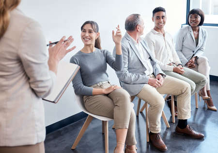 Please raise your hand when you hear your name. Shot of a group of new employees having a discussion with the recruiter at an office.の写真素材