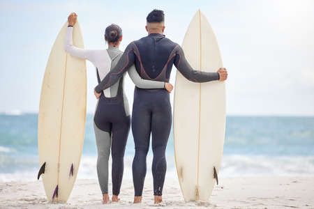 Ill ride every wave with you. Shot of a young couple holding surfboards at the beach.の写真素材