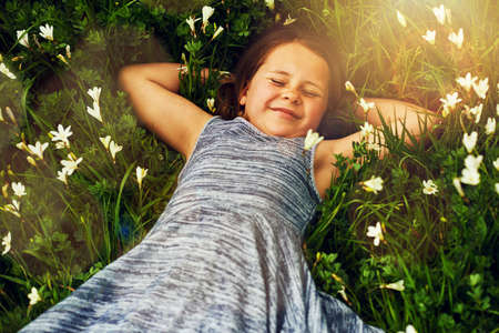 Making friends with the flowers. Shot of a cute little girl lying in a field of wildflowers outside.