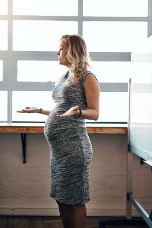 Managing her business and pregnancy. Shot of a pregnant businesswoman giving a presentation in the boardroom.の写真素材