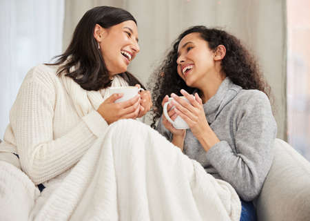 You know just how to make me laugh. Shot of two friends drinking coffee and talking at home.の写真素材
