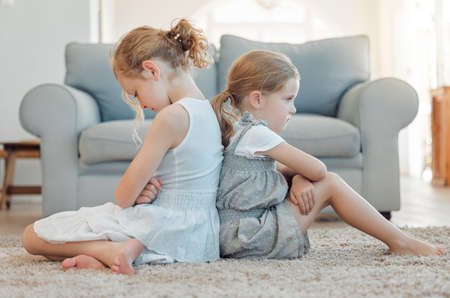 Im going to tell mom. Shot of two little girls sitting back to back and looking angry at home.の写真素材