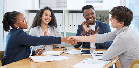 Concluding the meeting on a high note. Shot of businesspeople shaking hands during a meeting in an office.の写真素材