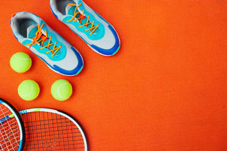 One needs really good shoes for this. High angle shot of tennis essentials placed on top of an orange background inside of a studio.の写真素材