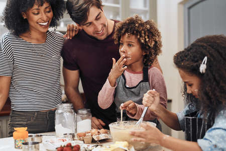 I can tell its going to be delicious. Cropped shot of a young couple baking at home with their two children.の写真素材