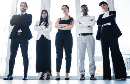 We mean business. Shot of a group of businesspeople with their arms crossed in an office.