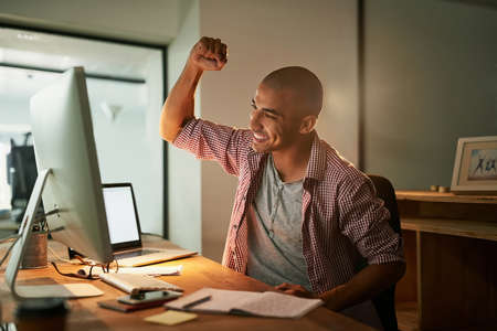 Finished my final deadline for the day. Cropped shot of a young designer doing a fist pump while working late in an office.の写真素材
