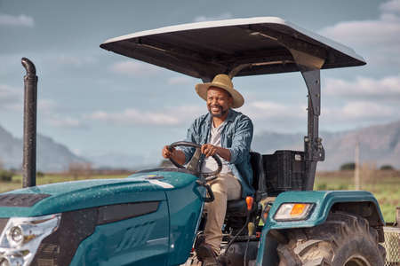 Off to the fields we go. Shot of a mature man driving a tractor on a farm.