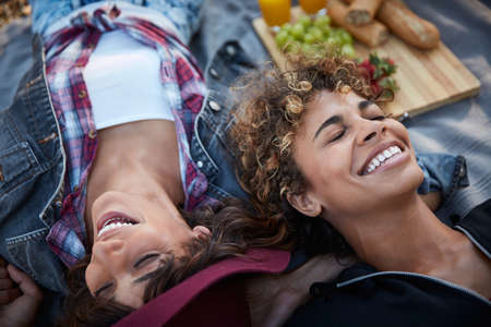 You make me laugh non-stop. Cropped shot of two young women lying on a picnic blanket.の写真素材