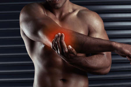 Stretch it out. Shot of an unrecognizable young man holding his elbow in pain during a workout.