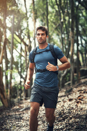 Hiking is his favourite hobby. Cropped shot of a handsome young man running during his hike in the mountains.の写真素材
