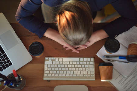 Is it time to go home yet. Shot of a tired young designer napping on her desk wile working late in the office.の写真素材