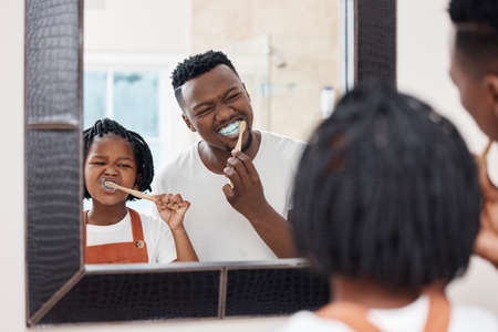 Make sure you get every tooth. Shot of a young father bonding with his daughter while they brush their teeth in the bathroom at home.の写真素材