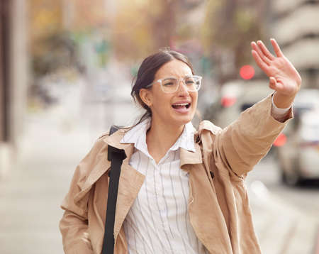 Panic is anxiety on fire. Shot of a beautiful young woman trying to hail a cab while out in the city.の写真素材