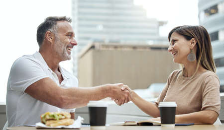 Business meetings made better over lunch. Shot of two businesspeople shaking hands while having...