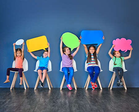 Fill the world with your voice. Studio shot of a diverse group of kids sitting on chairs and holding...