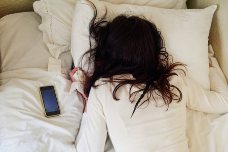 Nobody understand you better than your bed. High angle shot of a young woman lying in bed with tissues and her cellphone next to her.の写真素材