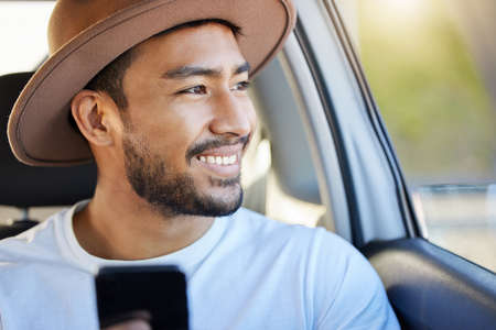 Roads are a record of those who have gone before. Shot of a young man sitting in a car while using his phone.の写真素材