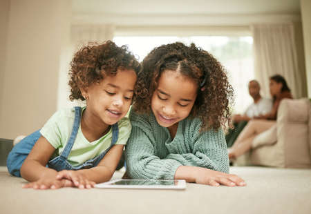 Nothing compares to a sisters love. Shot of two sisters using a digital tablet at home.の写真素材