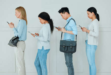 Theyre so easily bored these days. Shot of a group of businesspeople standing in a line at an office.の写真素材
