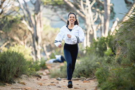 The trail is where she is most comfortable. Shot of a young woman going for a run.