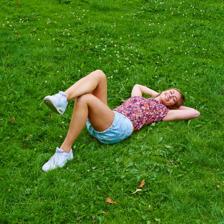 Frolicking in nature. Shot of a young woman relaxing on the grass in a park.