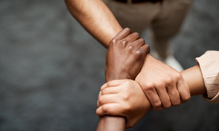 Hold onto your hunger for success. Shot of a group of businesspeople linking arms in solidarity in a...