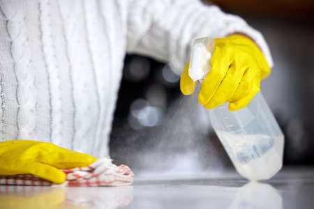 Always use a strong disinfectant. Shot of a woman spraying her kitchen counter to clean it.の写真素材