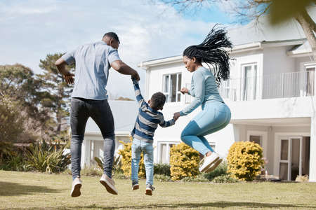 Who can jump the highest. Full length shot of a young couple bonding with their son in the garden.の写真素材