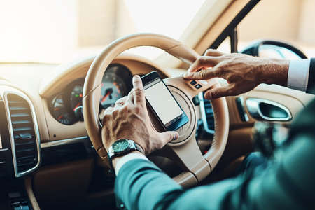 Checking where to go with my phone. Cropped shot of an unrecognizable man using a cellphone while driving.の写真素材