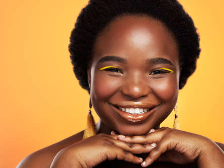 The more happy, the more beautiful. Studio shot of a beautiful young woman posing against an orange background.の写真素材