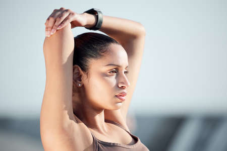 Be firm in your determination. Shot of a sporty young woman stretching her arms while exercising outdoors.の写真素材