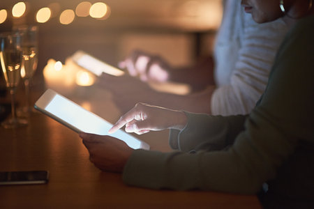 Connecting to a world that never sleeps. Cropped shot of a woman using a digital tablet at night.