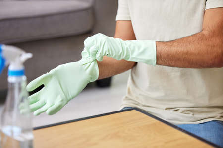 Have to protect my hands. Shot of an unrecognizable person cleaning a table at home.の写真素材