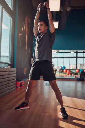 Put everything into each workout. Shot of a young man working out using a kettlebell in the gym.