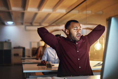 Must... stay... awake.... Shot of a young businessman looking exhausted while working late in an office.の写真素材