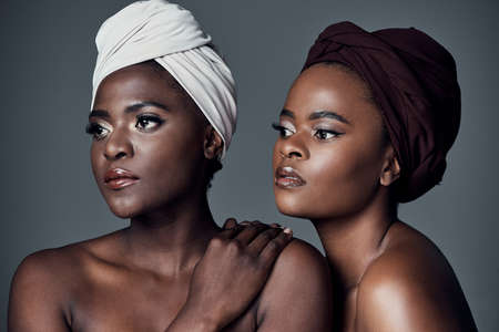 African Queens. Studio shot of two beautiful young women posing against a grey background.の写真素材