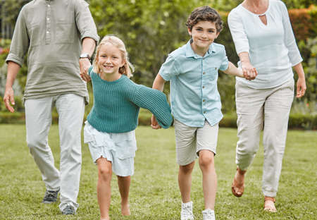 Lets go play. Shot of a little girl and boy running while outside with their parents.