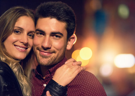 We make one good looking couple. Portrait of a happy young couple standing together outside at night.の写真素材