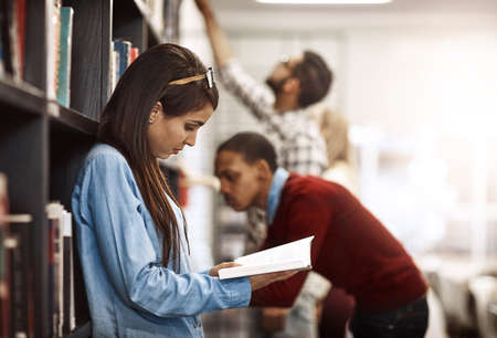 This book has just what I need to complete my project. Shot of a university student reading a book...
