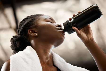 Time to rehydrate. Low angle shot of an attractive and athletic young woman drinking water during...