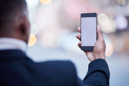 I stay connected from anywhere. Shot of an unrecognizable businessman using a phone in the city.の写真素材