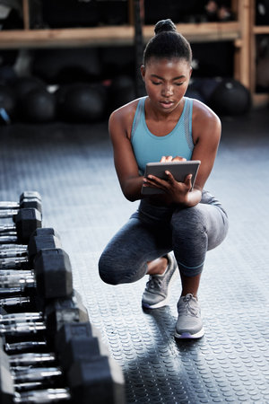 Another day at the gym. Shot of a fit young woman using a digital tablet in a gym.の写真素材