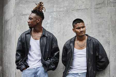 Just two brothers, born of the street. Cropped shot of two handsome young male gangsters chilling outside in the street.の写真素材