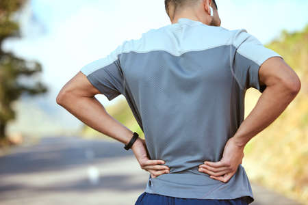 Take it one day at a time. Rearview shot of an unrecognisable man holding his lower back in pain...